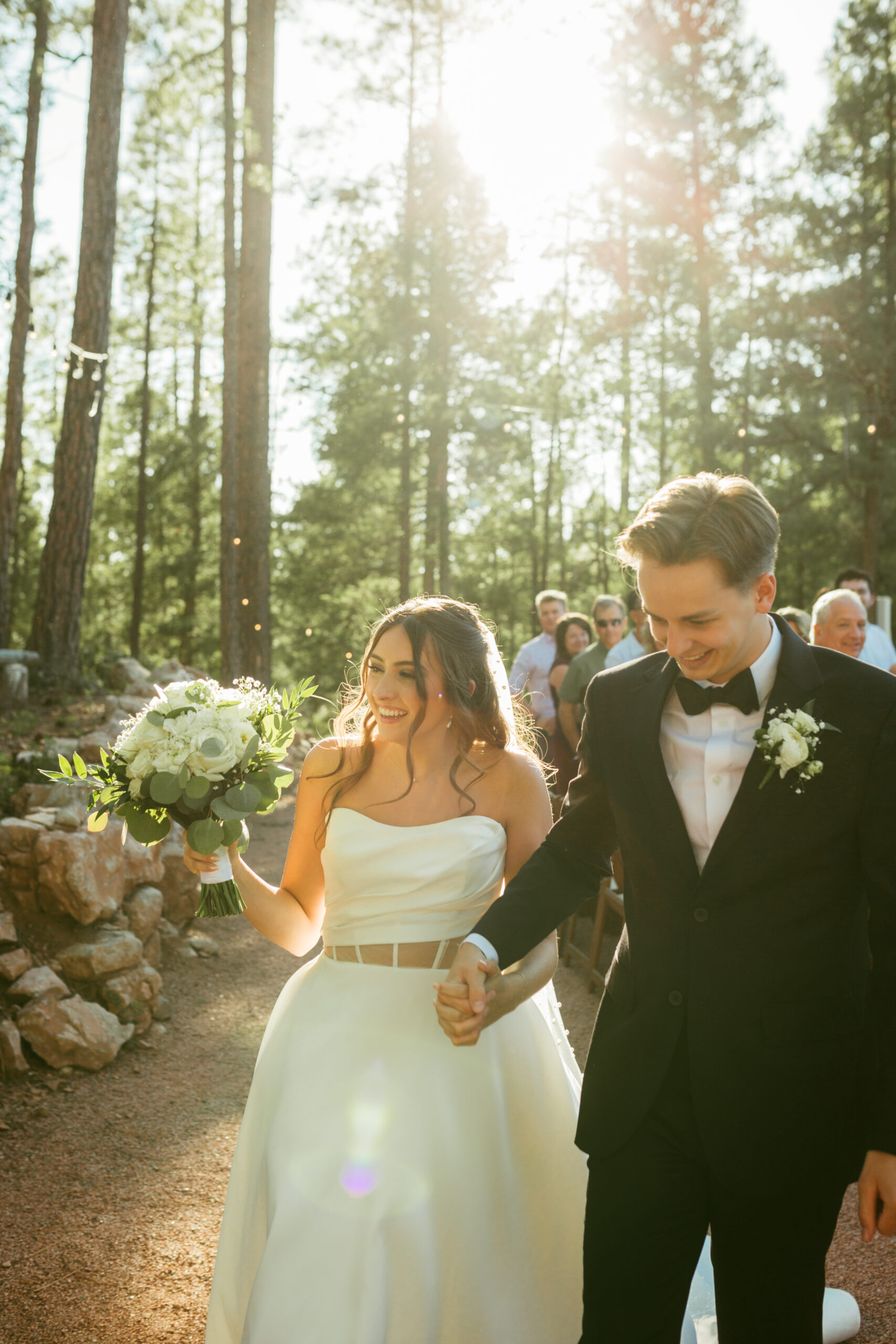 Husband and wife smiling while they walk down the aisle of their outdoor wedding ceremony.